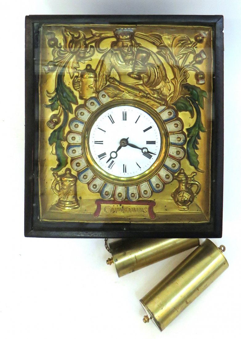 German Weight Driven Wall Clock: German Weight Driven Wall Clock: The clock face is decorated with a crowned royal figure with a stein and a vessel with the word Gambriniug at the bottom. Has a pair of brass cylindrical weights.