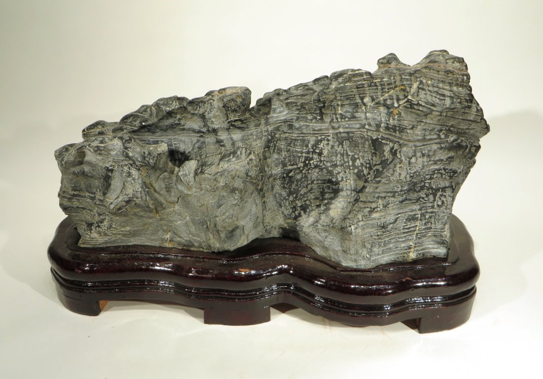 LING BI SCHOLAR'S STONE: Ling Bi Scholar's Stone: Horizontal scholar's stone resembling a low mountain range. Shows striated carving marks and veining. Deep trough carved in to one side. Polished on one side, left natural on