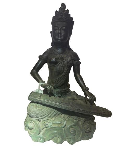 Bronze Figure of Saraswati, Goddess of Music and Learning: bronze sculpture depicting Saraswati, the Hindu goddess of knowledge, music, and the arts, shown seated gracefully and playing the veena, her traditional stringed instrument. The figure is adorned