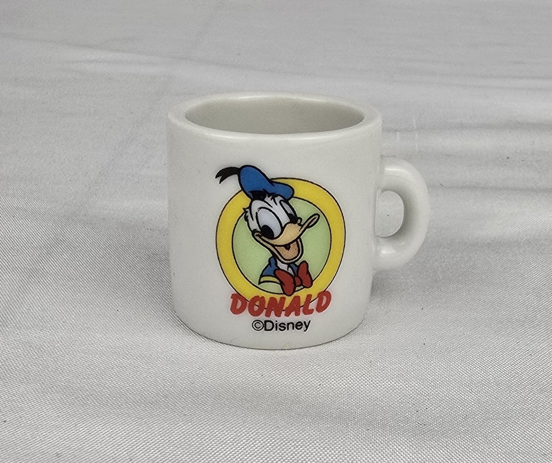 A Miniature Donald Duck Coffee Mug.: This is a miniature coffee mug featuring the classic Disney character Donald Duck. It measures 1.25? tall and is in excellent condition.