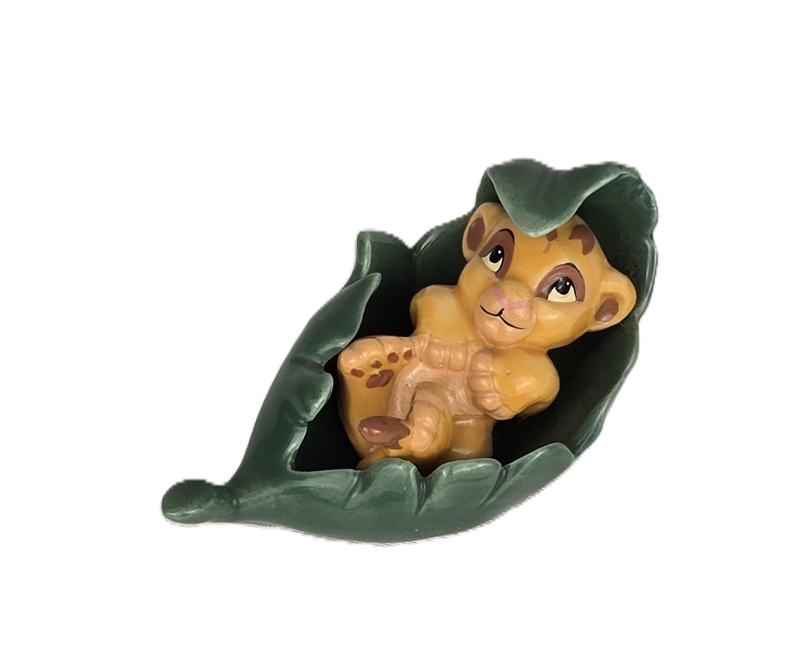 A Bone China Baby Simba Figurine.: This is a bone china figurine of baby Simba wrapped in a leaf. It is made in Japan. It is just under 1.5? tall and is 3? long.