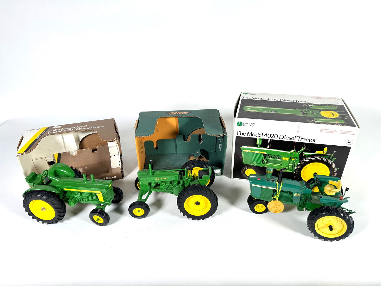 Lot of three John Deere Ertl Die-cast tractors with boxes: Lot of three John Deere Ertl Die-Cast tractors with boxes. Includes; 1956 John Deere 820 diesel tractor, John Deere, wide front model G, and model 4020 diesel tractor. All very nice. Size: 10“ x 6��