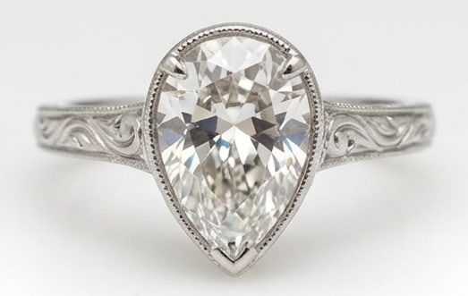 IGI Lab Grown 3.00 Ct Pear Shape Diamond Ring – Vintage Bezel/Prong Hybrid with Scroll Engraving: IGI Certified Lab Grown Diamond Center Stone Color E-F Clarity VVS1-VS1 Designed to stand out, this ring presents a 3.00 carat lab grown Pear Shape center diamond. Set in White Gold , the ring is styl