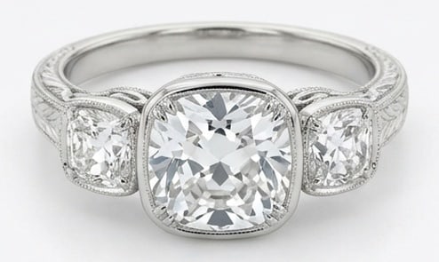 IGI Lab Grown 4.00 Ct Cushion (Old Mine Look) Diamond Ring – Vintage Three-Stone Cushion Bezel Set: IGI Certified Lab Grown Diamond Center Stone Color E-F Clarity VVS1-VS1 Side Stone Lab Grown Diamond Sophisticated and modern, this ring is defined by a 4.00 carat lab grown Cushion (Old Mine Look) ce