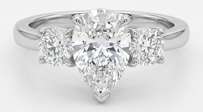 Lab Grown 4.00 Ct Pear Shape Diamond Ring – Three-Stone Pear with Round Sides – / in 14K White: Beautifully styled, this ring is anchored by a 4.00 carat lab grown Pear Shape center diamond. Featuring a Three-Stone Pear with Round Sides aesthetic, balancing bold geometry with wearable elegance.