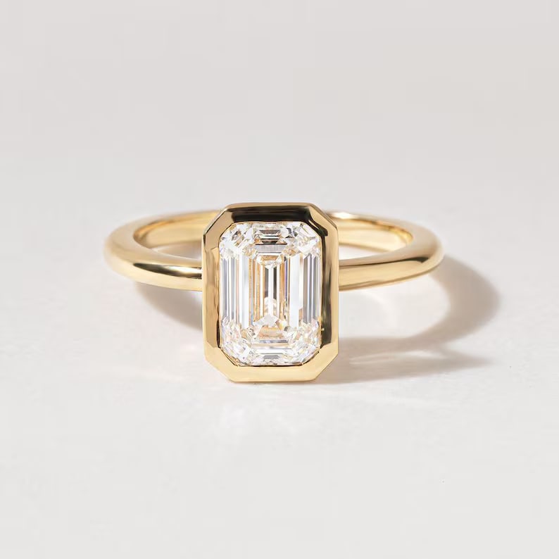 Luxury GIA Certified 2.00 Ct Emerald Cut Lab Grown Diamond Ring in 14K Yellow Gold: An elegant and luxurious engagement ring featuring an approximately 2.00 carat lab grown diamond in a refined emerald cut cut. Beautifully crafted in premium 14K Yellow Gold, this ring showcases a bez
