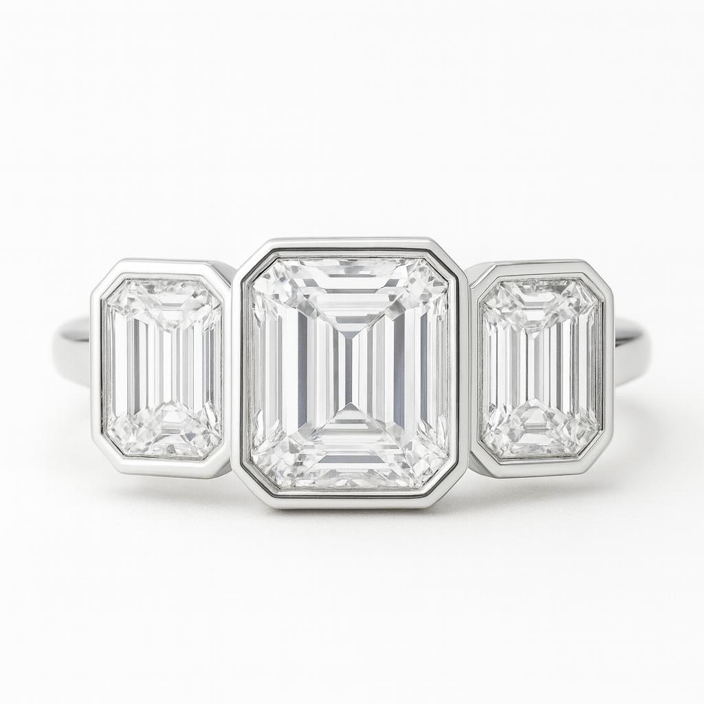 5.50 CT Lab Grown Emerald Cut Diamond Three-Stone Ring in 14K White Gold: Modern elegance defines this 5.50 carat lab grown emerald cut diamond three-stone ring. Featuring a bold emerald cut centerpiece, bezel-set and flanked by two matching emerald cut side stones. Crafted