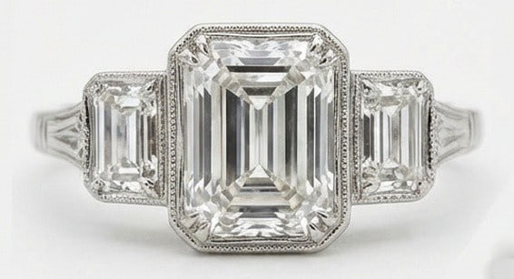 Lab Grown 5.00 Ct Emerald Cut Diamond Ring – Art Deco Three-Stone Bezel Set (Step Cut) – / in: Designed to stand out, this ring presents a 5.00 carat lab grown Emerald Cut center diamond. Set in White Gold , the ring is styled with art deco three-stone bezel set (step cut) details that define i