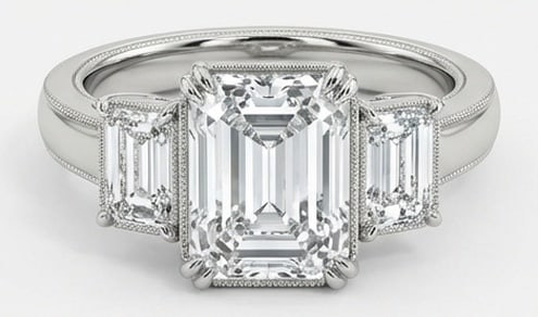 Lab Grown 5.00 Ct Emerald Diamond Ring – Three-stone setting with milgrain bezel details on: Classic with a contemporary edge, this ring spotlights a 5.00 carat lab grown Emerald center diamond. Set in White Gold, the ring is styled with three-stone setting with milgrain bezel details on emer