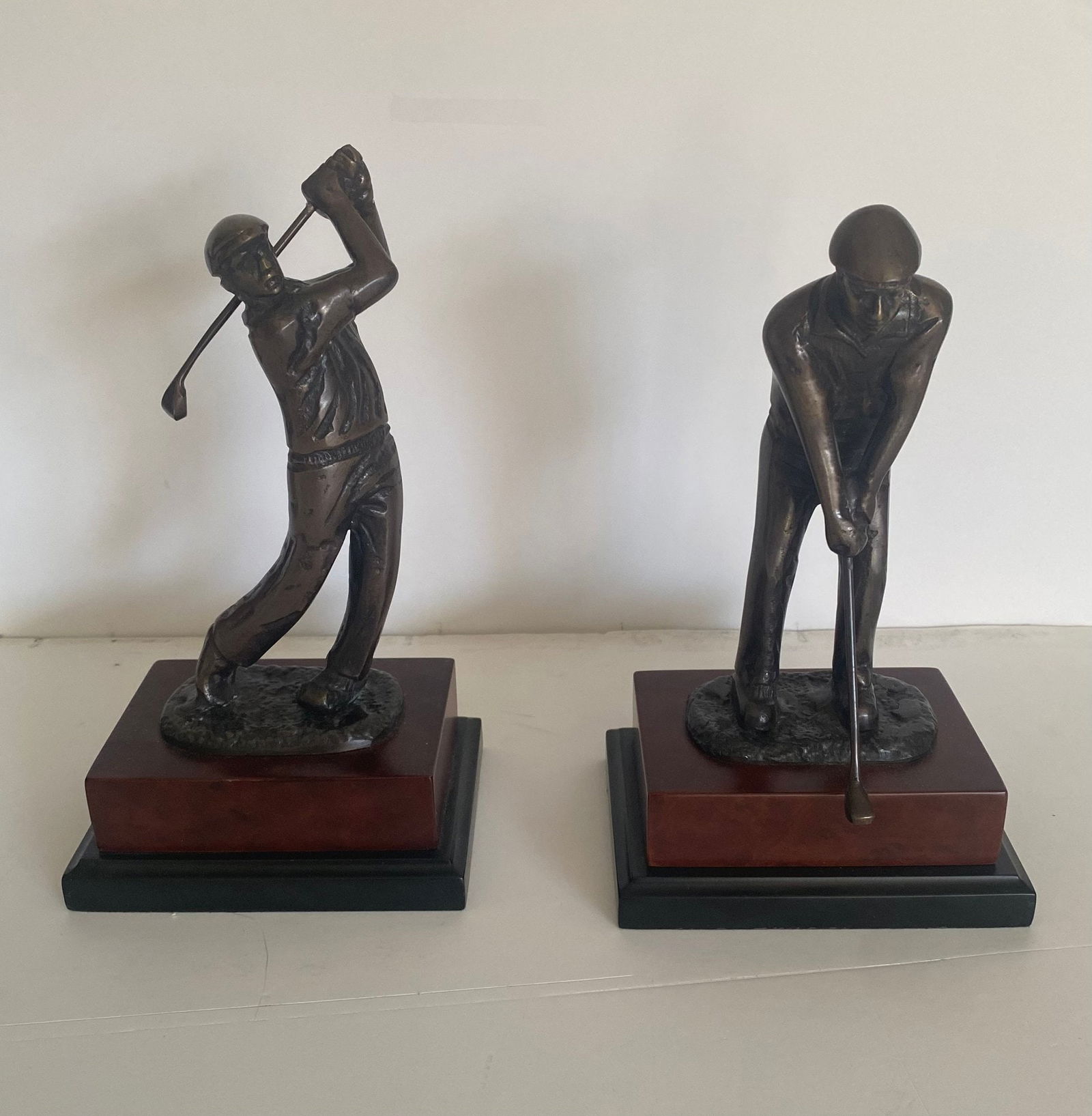 2 Bronze Golf Themed Sculptures On Wood Pedestal: These are golf-themed statues depicting golfers in various poses. They are often used as decorative pieces or awards. Features: Bronze material, wood pedestal
