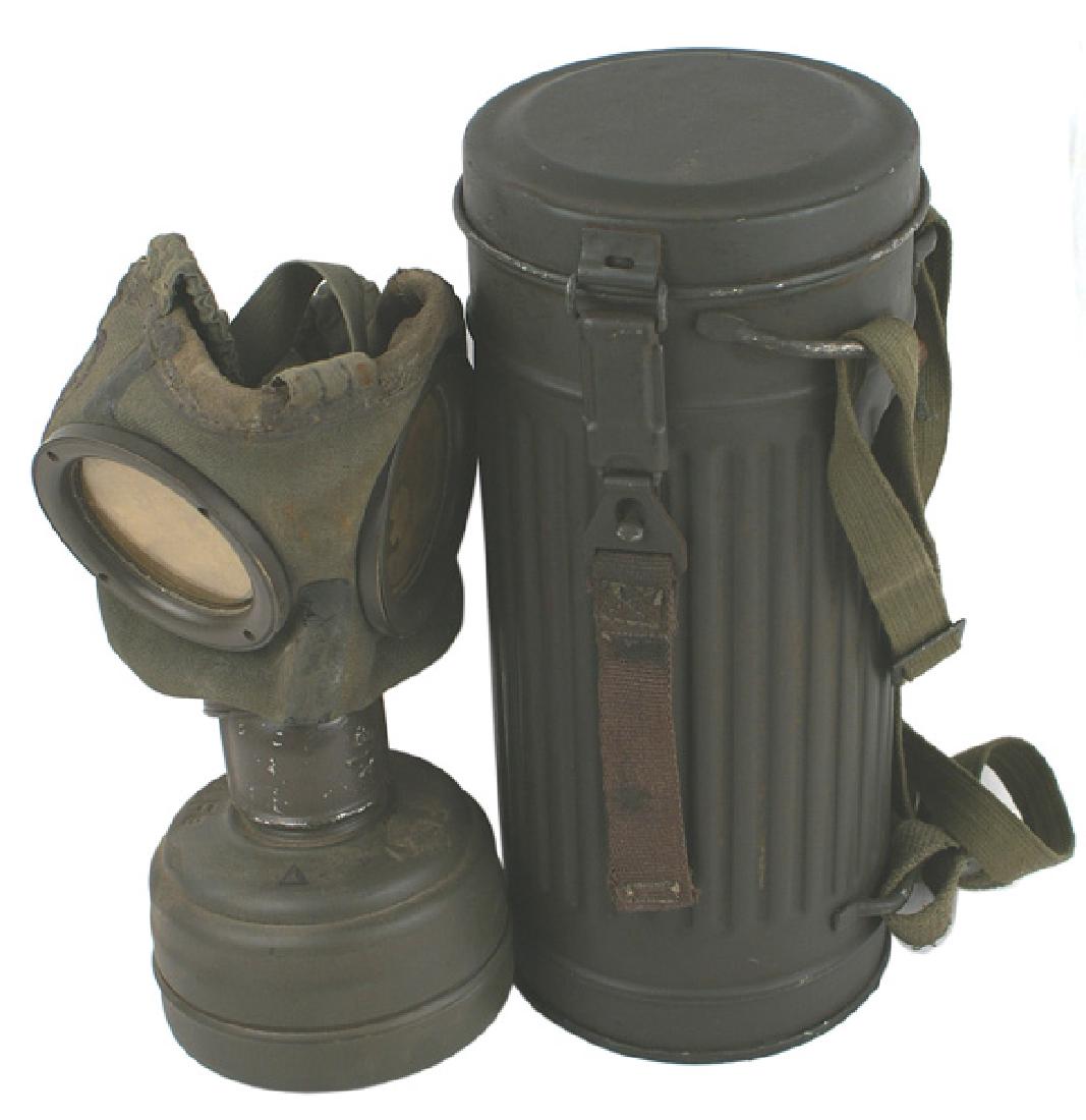 German WWII Army gas mask: N-009 German WWII Army gas mask. OD metal canister with hinged cover/pull strap, shoulder strap and belt hook strap. Heavy cloth mask with both lenses and filter can. Side of mask is stamped with a la