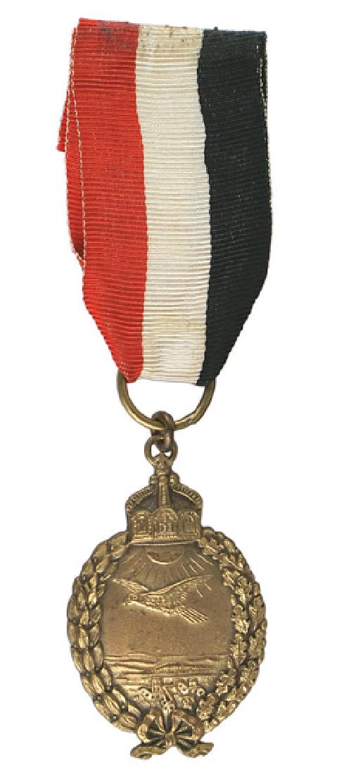 Prussian Navy Land Pilot Badge Prinzen size: B-037 Prussian Navy Land Pilot Badge. Prinzen size, mounted on a medal ring suspension. Age toned gilt finish. Reverse has a crescent hallmark and "800". Red/white/black ribbon. II