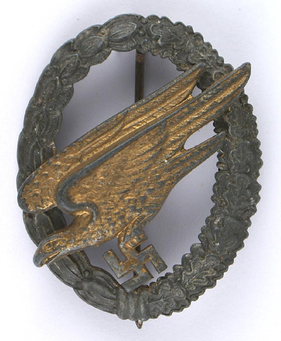 German WWII Luftwaffe Paratrooper Badge: B-122 German WWII Luftwaffe Paratrooper Badge. Age darkened gilt diving eagle/swastika shows some wear. Dark metal oval oak/laurel leaf wreath. Reverse is marked "B&NL". Definitely a "salty" field-wor
