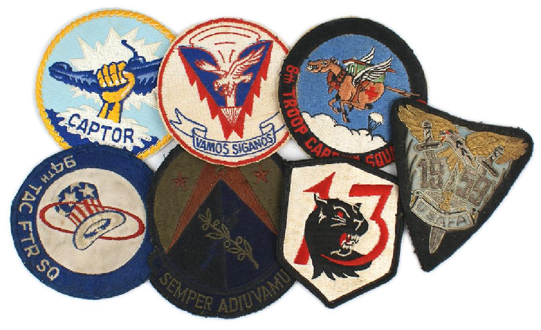 U.S. WWII and later jacket patches: H-151 Lot of 7 embroidered U.S. WWII and later jacket patches: (1) "6th TROOP CARRIER SQUADRON" - WWII. (2) "VAMOS SIGANOS". (3) Unknown - Olive branch/lightning bolt on a black pyramid on a red pyram