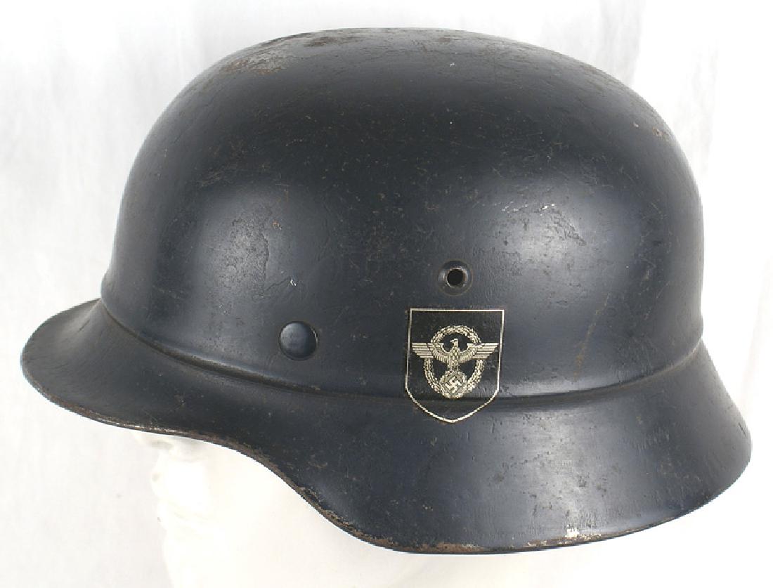 German WWII Police M1940 helmet: E-030 German WWII Police M1940 helmet. Bead extending around rim of the skull. Some wear to the dark finish but both decals are intact. Eagle/swastika/wreath would rate 99% and the swastika shield 95%