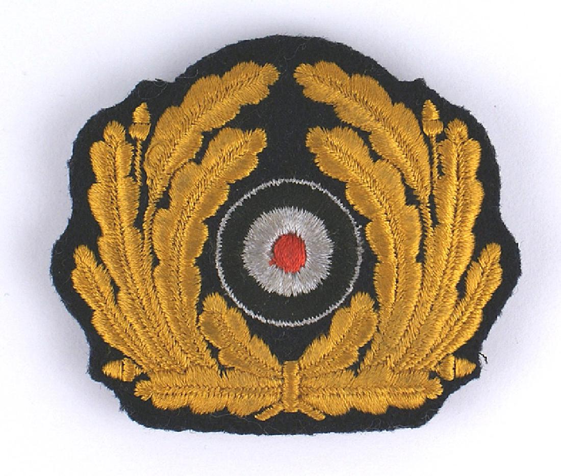 German WWII Navy cap wreath rosette: E-128 German WWII Kriegsmarine officer's embroidered peaked cap wreath/rosette. Yellow-gold leaves with a silver/red/black rosette. Padded type. II