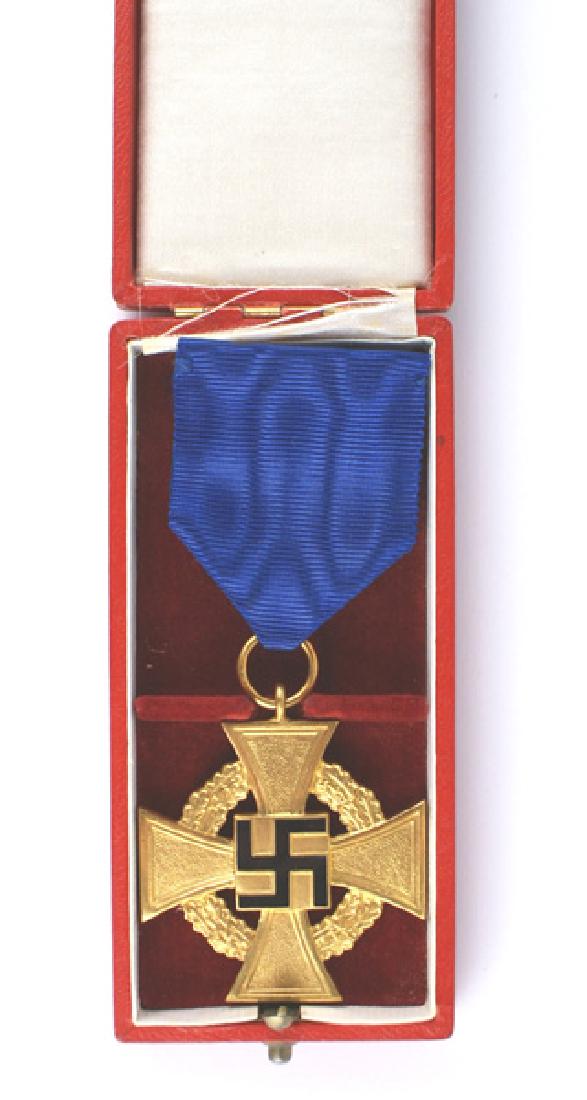 German WWII 40-year Loyalty Cross Medal: B-135 German WWII 40-year Loyalty Cross. Gilt with a black enameled swastika. Pin-back blue ribbon. The original red leather presentation case has a gilt oak leaf wreath with "40" on the lid. Case sho