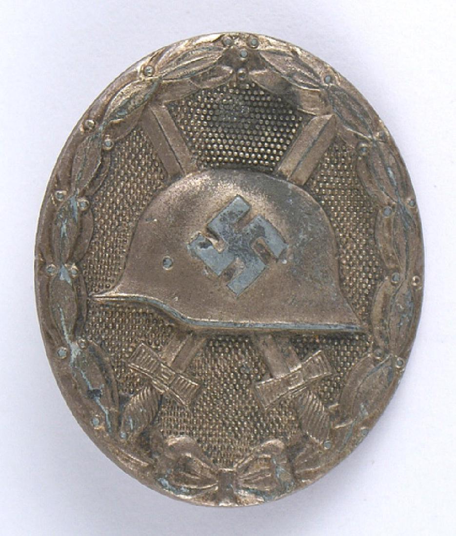 German WWII 1939 Wound Badge Silver: B-191 German WWII 1939 Wound Badge-Silver. Swastika on helmet with crossed swords. Pebbled background and laurel leaf border. Reverse marked "L/14" (L.Chr.Lauer in Nurnberg). Solid type. Shows some we