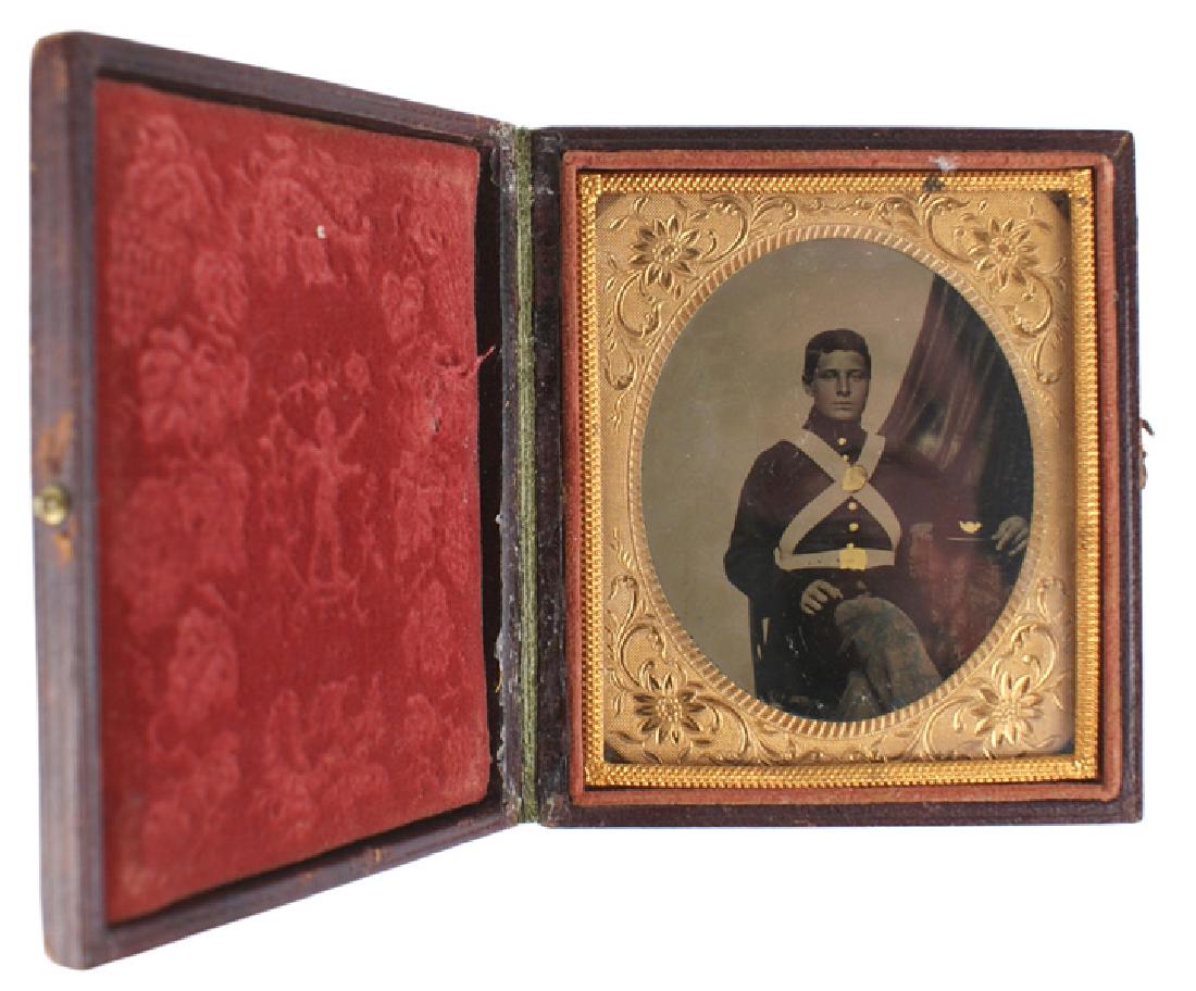 Ambrotype photo of Civil War cadet: K-035 Ambrotype of a seated Civil War cadet. Subject is wearing a high collar tunic with applied gold buttons and belt plates on the white cross straps and belt. Tunic is probably a dark navy blue and