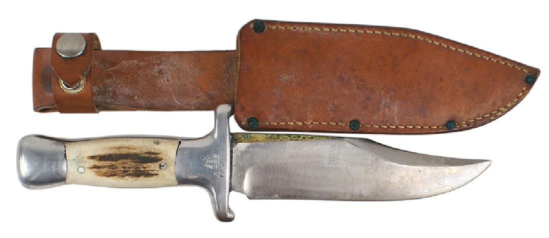 Ruana Bowie-type hunting knife WWII era: D-105 Ruana Bowie-type hunting knife. Polished steel rounded pommel and one-piece crossguard/tang (Stamped "R.H. RUANA - BONNER MONTANA". 5 7/8" Bowie-type blade with a 3" clip point. Brown leather sc
