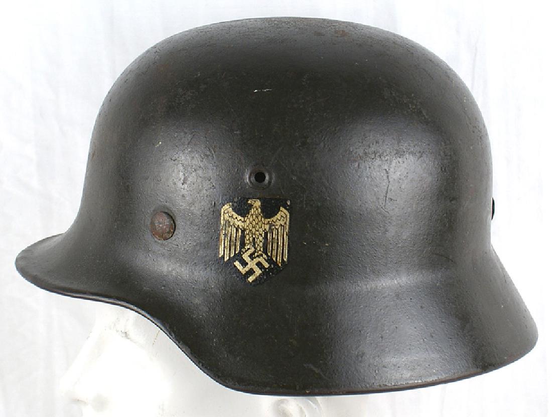 German WWII Army M1940 single decal helmet: E-018 German Army M1940 single decal helmet. 65% original dark green finish showing some wear and most of an old application of gloss. 98% eagle decal. Original leather chinstrap, dated "194..". Tan l