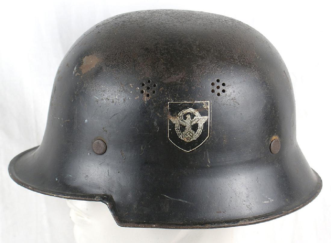 German WWII Police double decal helmet: E-041 German Police "square dip" double decal helmet, 60% original black finish. "Dimpled" top is dented. 90% eagle decal and 60% swastika shield. Original leather chinstrap. Tip is missing. Tan leath