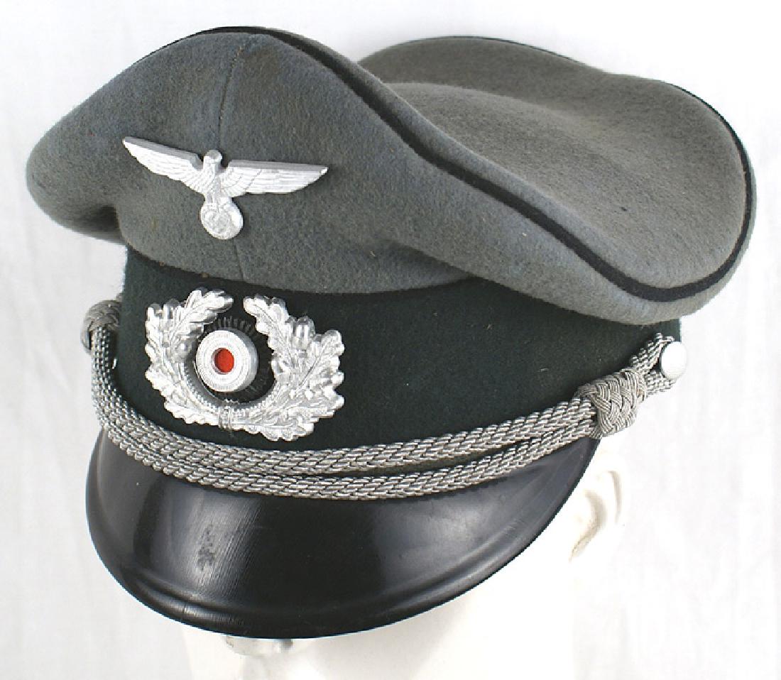 German WWII Army Pioneer officer peaked cap: E-085 German WWII Army Pioneer officer peaked cap. Black piped dark green band and feld-grau body. Good "crusher" shape. High peak. Metal eagle/swastika insignia. Silver cord chinstrap. Black vulcan v