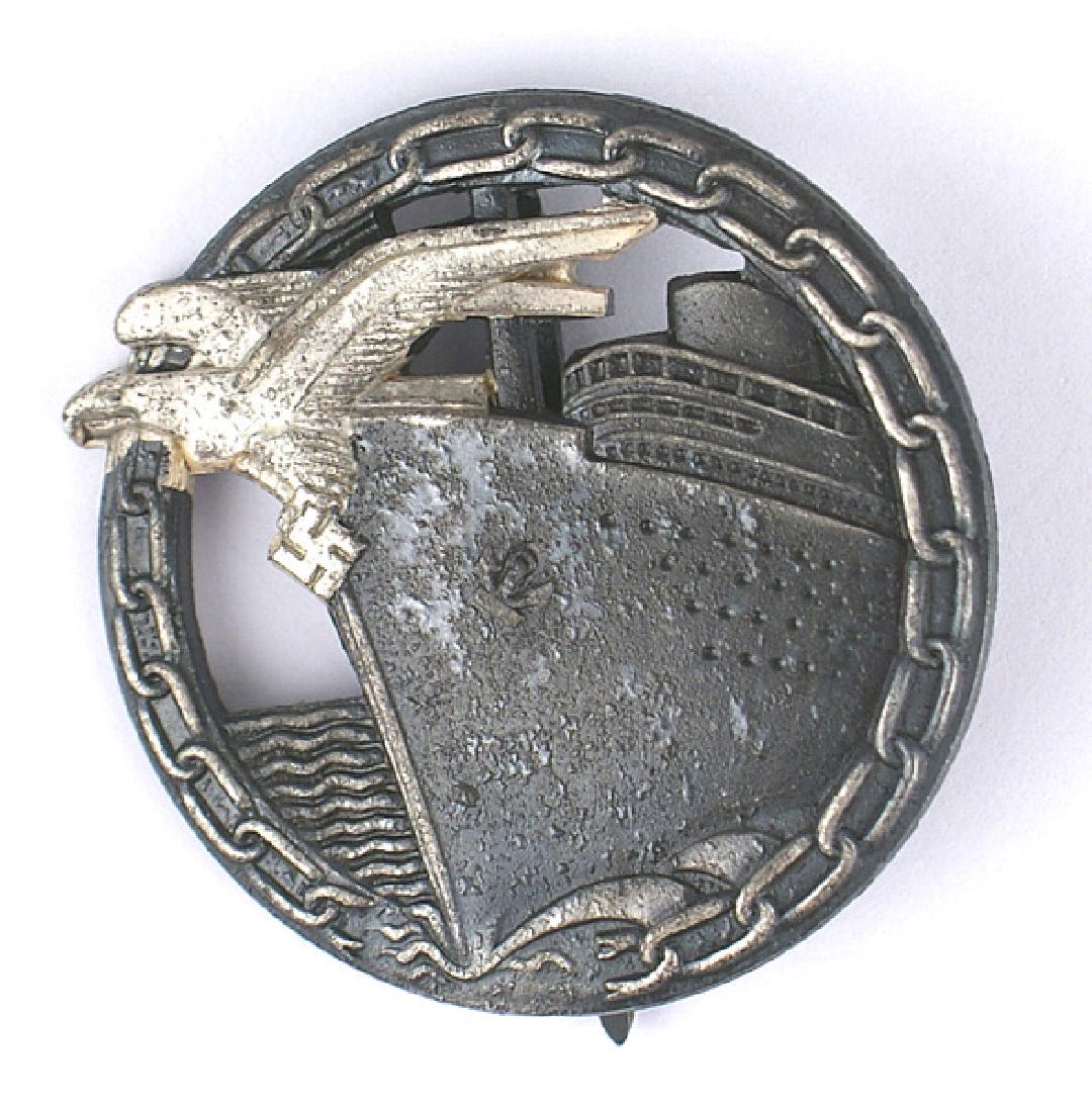 German WWII Navy Blockade Runner Badge: B-157 Navy Blockade Runner Badge. Open round wreath holding a gun-metal ship's bow with a silvered eagle-swastika and link chain border. Reversed marked "FEC. OTTO PLACZEK BERLIN...". Wide pin. A good