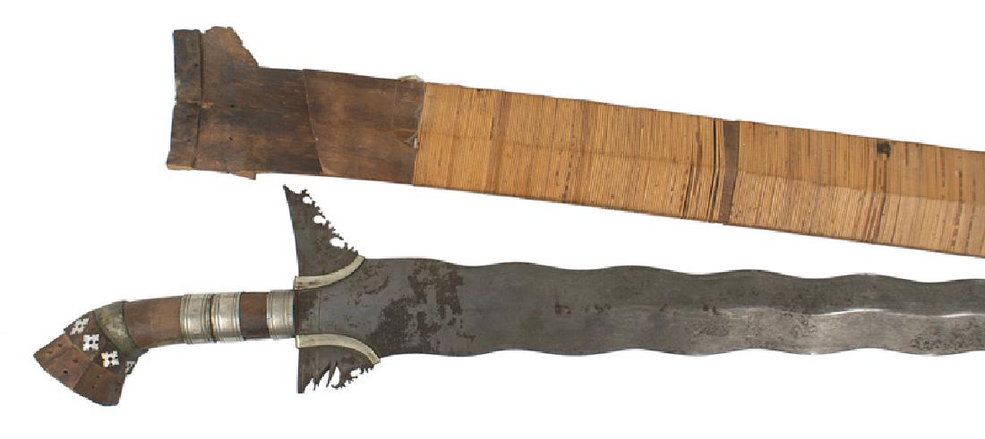 Moro Kris: R-016 Moro Kris. Two inch wide, 22 3/4" wavy blade with a curved tip. Two silver bands around the ricasso. Wood grip wound with three silver bands. Octagonal - shaped pommel with inlaid abalone "snowf