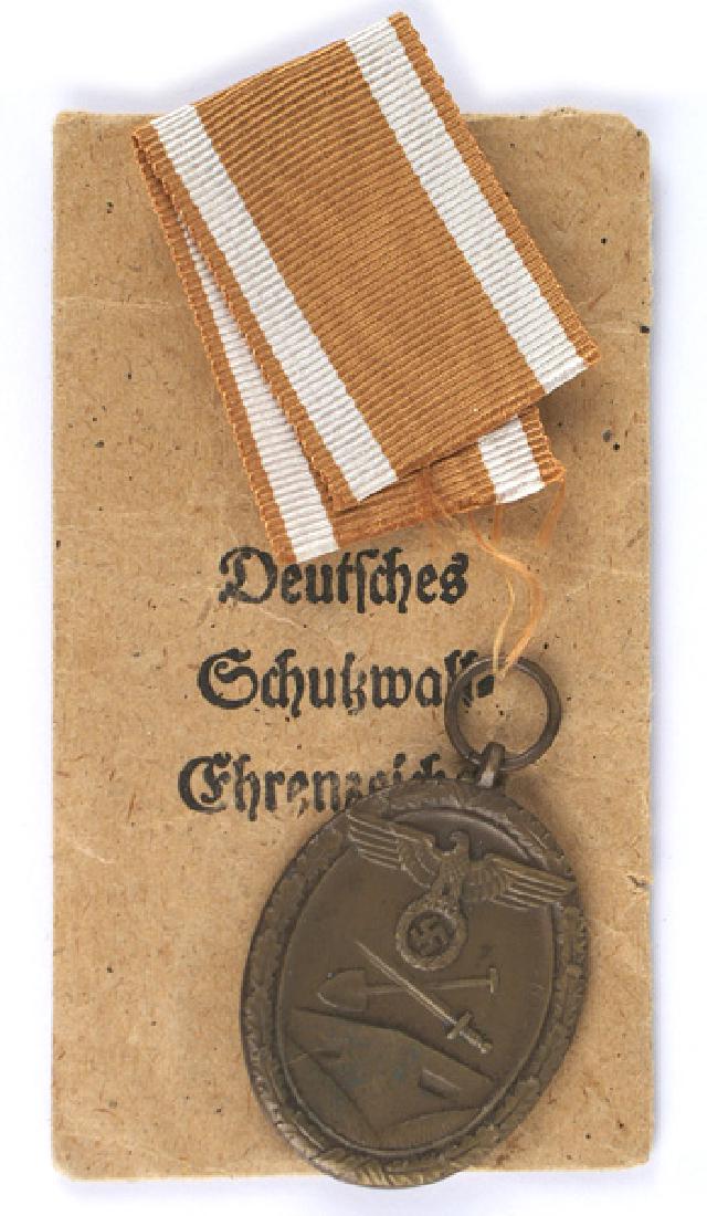 German WWII West Wall Medal: B-130 West Wall Medal. Large eagle/swastika crossed shovel/sword above a bunker. Awarded to all personnel who helped construct Germany's West Wall Fortifications. With ribbon. With the original paper