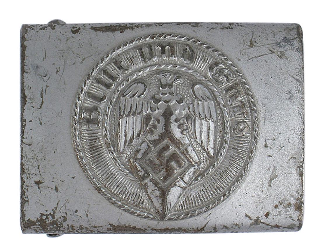German WWII Hitler Youth belt buckle: H-008 Hitler Youth belt buckle. Dulled gray steel with a relief eagle/diamond/swastika and "Blut und Ehre". Some wear on the edges. II