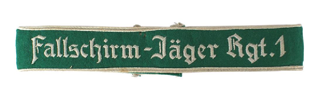 German WWII Luftwaffe Fallschirm Jager Rgt.1 cufftitle: H-025 Luftwaffe "Fallschirm - Jager Rgt.1" cufftitle. Worn by officers of the 1st Parachute Regiment. Relief embroidered Gothic type silver lettering and piping on a green cloth band. Three minor "bit