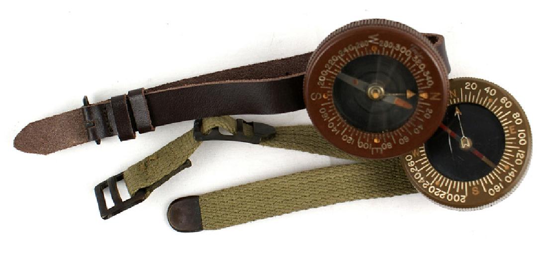 US WWII Corps of Engineers wrist compasses: N-040 Lot of 2 US WWII Corps of Engineers wrist compasses. Large bakelite type. Degrees/minutes marked along rim. Reverse has name of maker. One with a leather strap, the other web. II