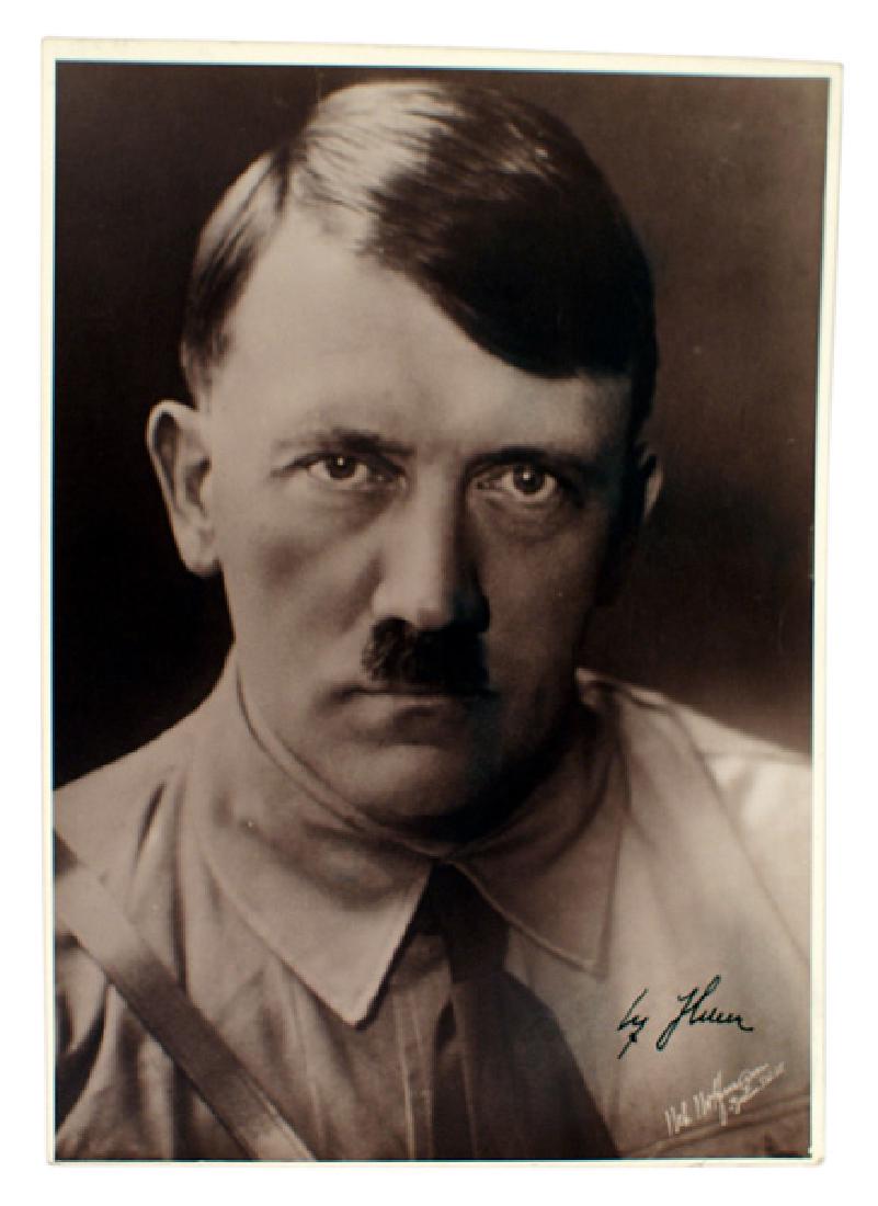 Early Heinrich Hoffman photo signed by Hitler: A-003 Early Heinrich Hoffman portrait photo of Adolf Hitler. Subject is wearing a "brown shirt", necktie and shoulder cross - strap. Bold black ink "Adolf Hitler signature. 9 7/8" x 6 7/8". II+