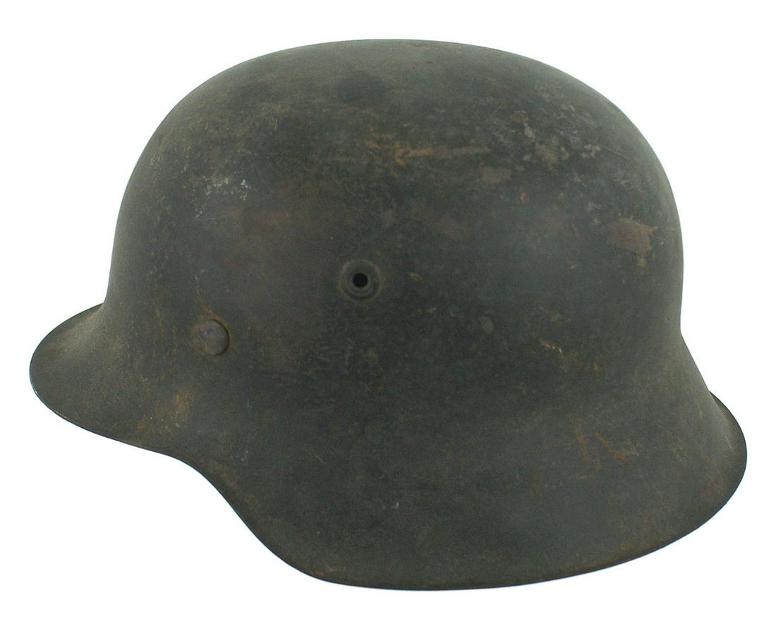 German Army M1942 helmet: E-022 German Army M1942 helmet. 80% original O.D. finish with "patches" of an underlay of a lighter camouflage visible. Original leather chinstrap (old repair) and a tan leather drawstring liner. II