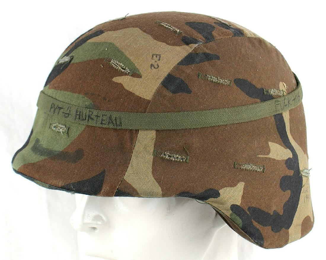 US PASGT Kevlar helmet: E-078 U.S. PASGT Kevlar helmet. Woodland pattern camouflage cover. Two "pulls" on the web chinstrap. (Shape similar to the German M1935). II