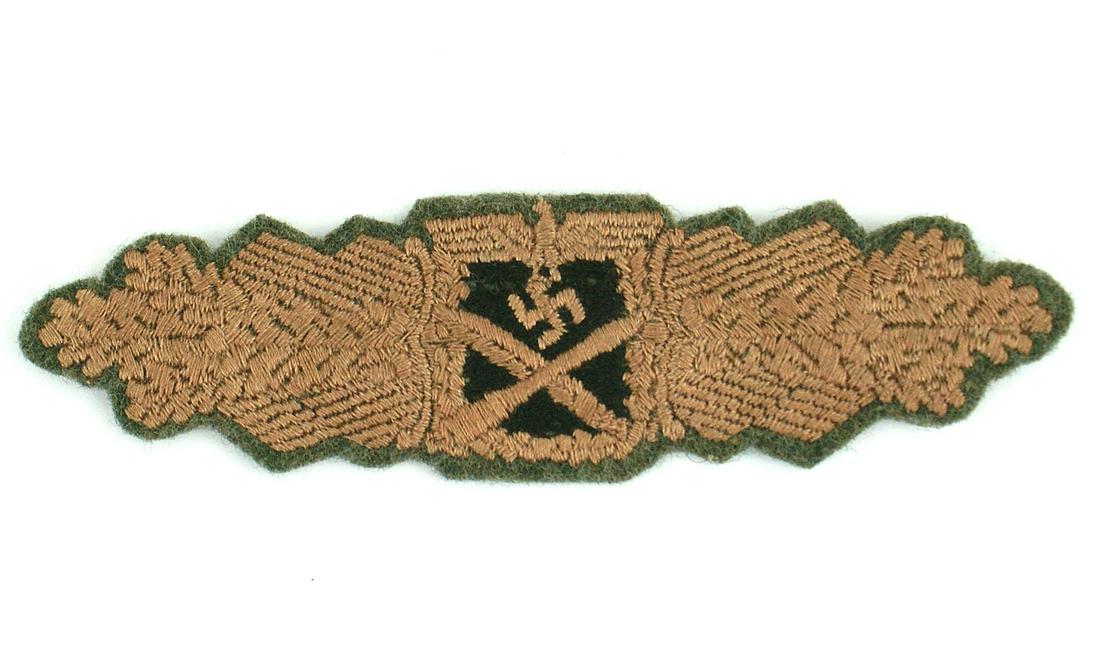 Embroidered German WWII Close Combat Bar: B-056 Embroidered German WWII Close Combat Bar in Bronze. Eagle/swastika over a crossed bayonet/grenade, on a black center, on a spray of oak leaves. Feld grau border. A quality badge. Scarce. II+