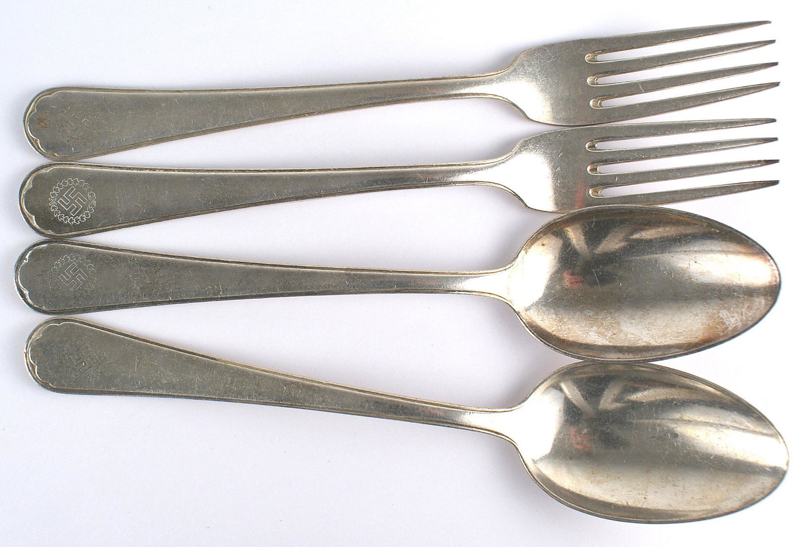 Lot of 4 Hotel Deutsche Hof Nurnberg silverware: A-011 Lot of 4 pieces of Hotel Deutsche-Hof Nurnberg nickeled silver flatware. Includes: (1) Two 8 3/8" serving spoons. (2) Two 8 3/8"forks. All pieces have an engraved swastika within an oak leaf wre