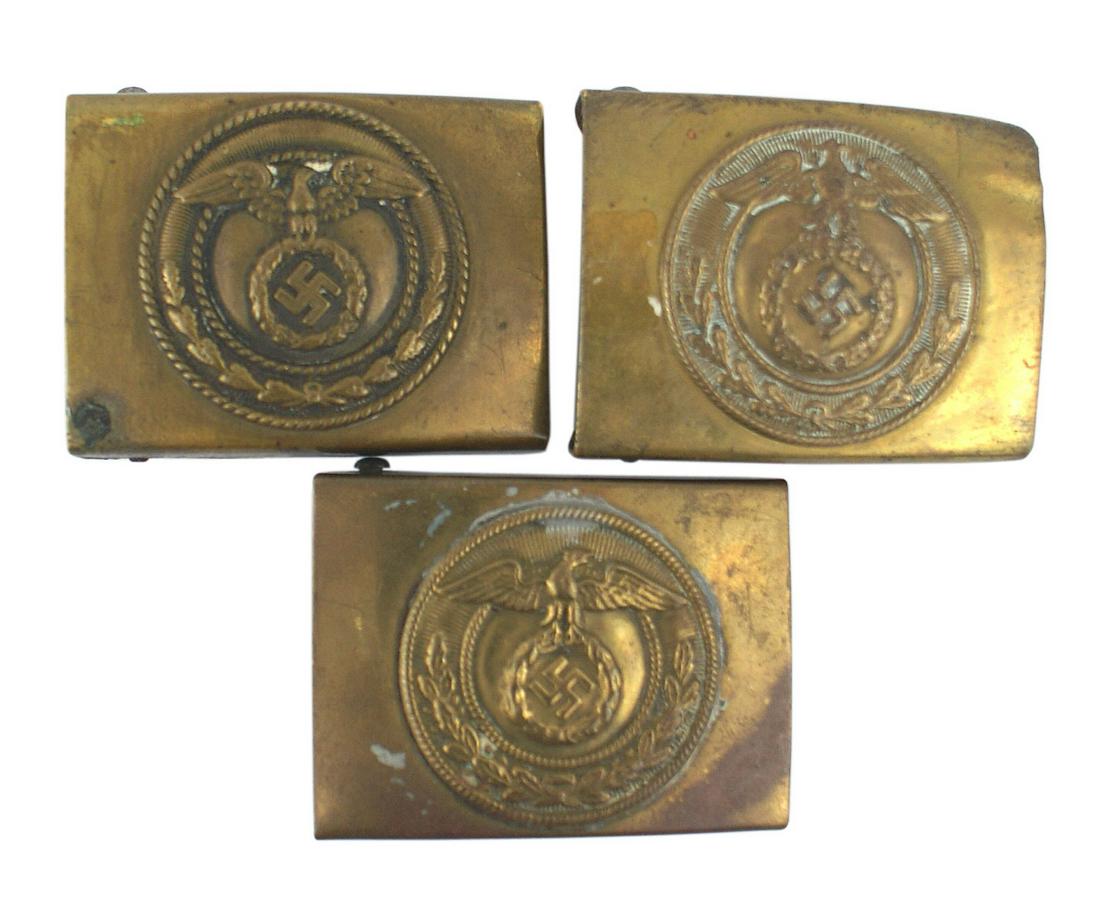 Lot of 3 German WWII SA belt buckles: H-010 Lot of 3 variation brass German WWII SA belt buckles. All have a tilted swastika within an oak leaf wreath, but the positioning of the eagle is different on each. Circa 1929-1936. II