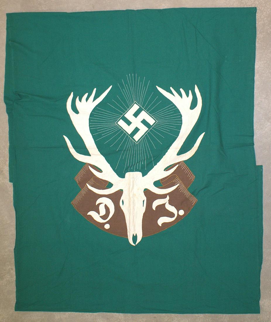 German WWII Hunting Association flag: H-059 German Hunting Association wall banner. Large white size 56" x 44" sketal stag's head/white swastika "DJ" on a brown ribbon-all on a green field. Missing top sleeve as banner was probably cut do