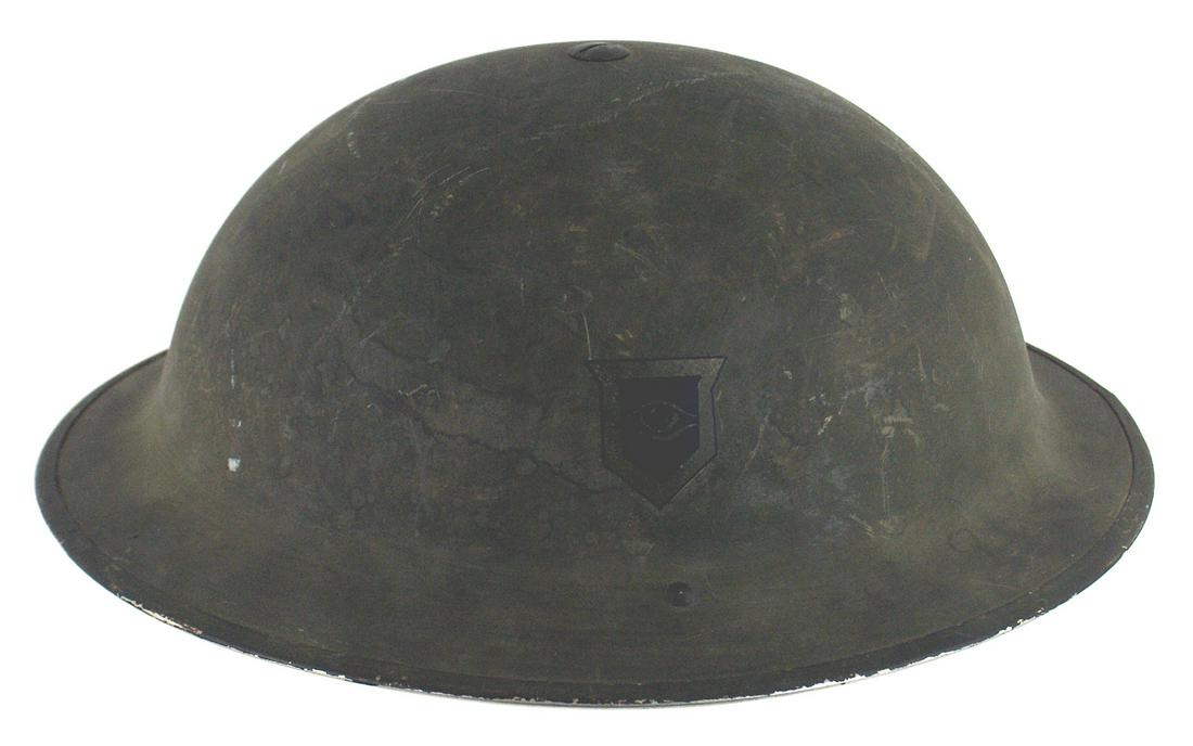 British WWII Tommy helmet First model: E-063 WWII British "Tommy" helmet. First model with a partial spring chinstrap. Liner in good shape and dated: "1943". Helmet has unusual insignia consisting of a decal of an eye within a shield on le