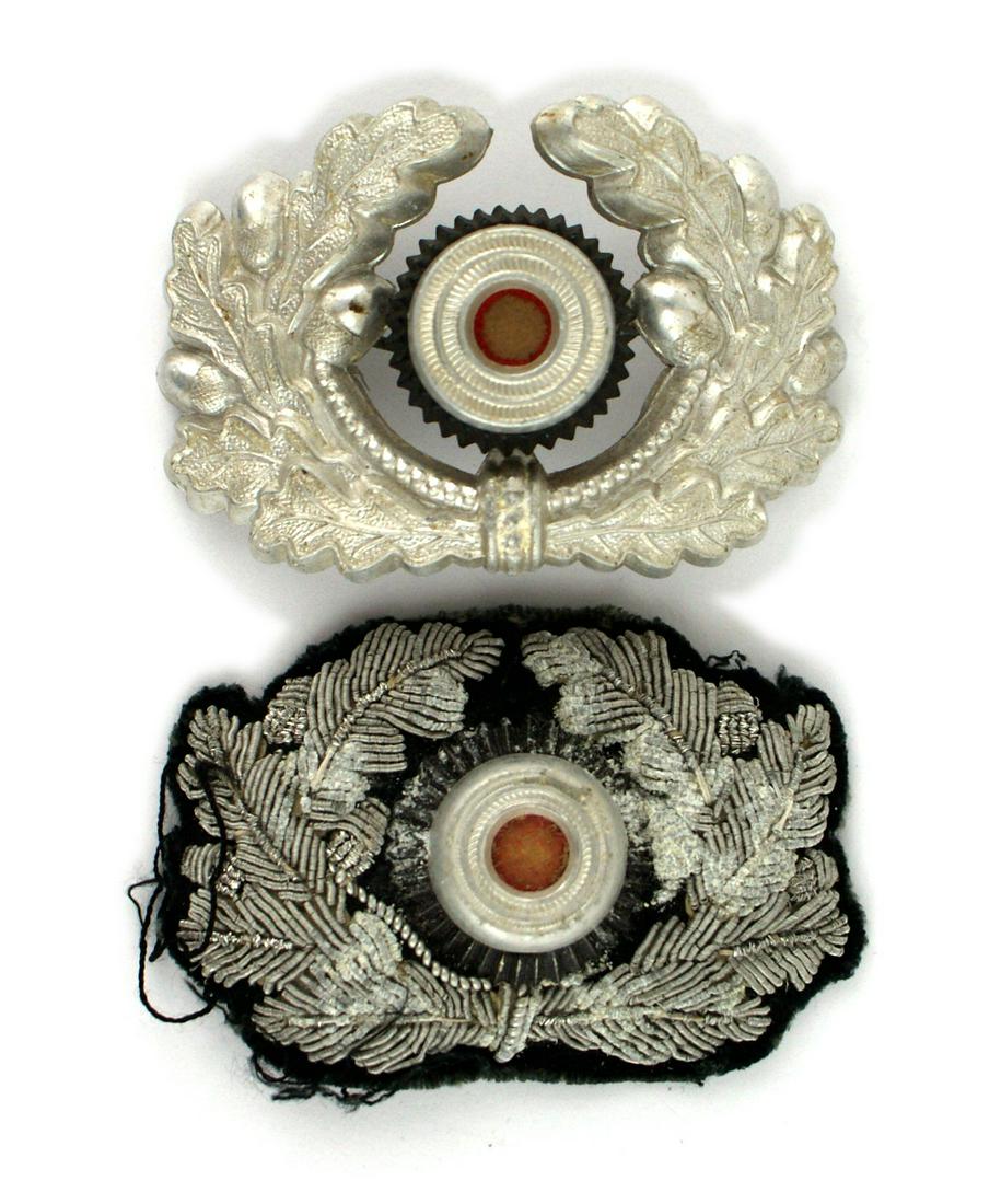 Lot of 2 German WWII Army officer cap wreaths: E-123 Lot of 2 Army Officer peaked cap wreaths; (1) Relief embroidered silver bullion with a metal "Bulls-eye" rosette. Shows some age. (2) Same but all metal. II