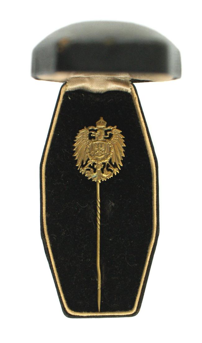 Imperial German stickpin Prussian eagle cased: B-006 Imperial German stickpin. Age toned gilt cut-out crowned eagle with a chest shield bearing a Prussian eagle - within a "collar" order. Long spiral stickpin. Coffin shaped black leather, silk/vel