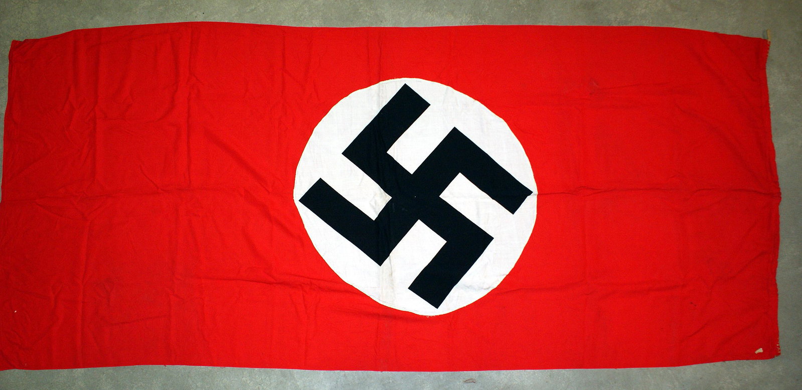 German WWII NSDAP banner flag: H-062 N.S.D.A.P. banner. Large Black swastika printed on a 30" diameter white center - sewn to a red 98" x 44" field. Rope loops in two corners. II