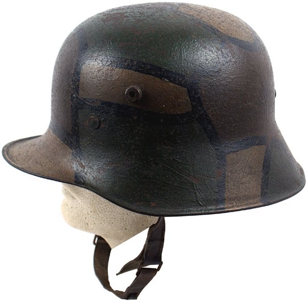German WWI M1918 camo helmet: E-19 M1918 camouflage helmet. Aged patina on black outlined green, dull yellow-brown "stained glass" pattern. Three double-tongued pad liner shows some expected wear. Original period Austrian type wid