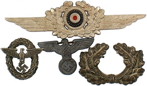 German WWII Army hat insignia: E-201 Lot of 4 metal peaked cap insignia. Includes: (1) Army oak leaf wreath. Age toned. (2) Luftwaffe winged wreath/rosette. (3) Political type cap eagle. (4) Fire Police first type eagle/swastika/wr