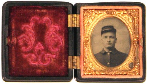 Civil War Ambrotype portrait solider: K-45 - Ambro type portrait of a solider wearing a kepi. 1 1/2" x 1 1/4". Gilt frame with embossed floral motifs. Velvet lined inner cover. Gutta percha hinged case with embossed floral work. II.....$5