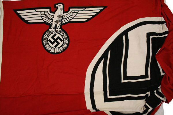 German WWII Military Garrison flag: H-107 - Military Garrison Flag. Massive white outlined black swastika within a white circle. Large black outlined white eagle/swastika in left corner. Rope sewn into sleeve with end loops and large sn