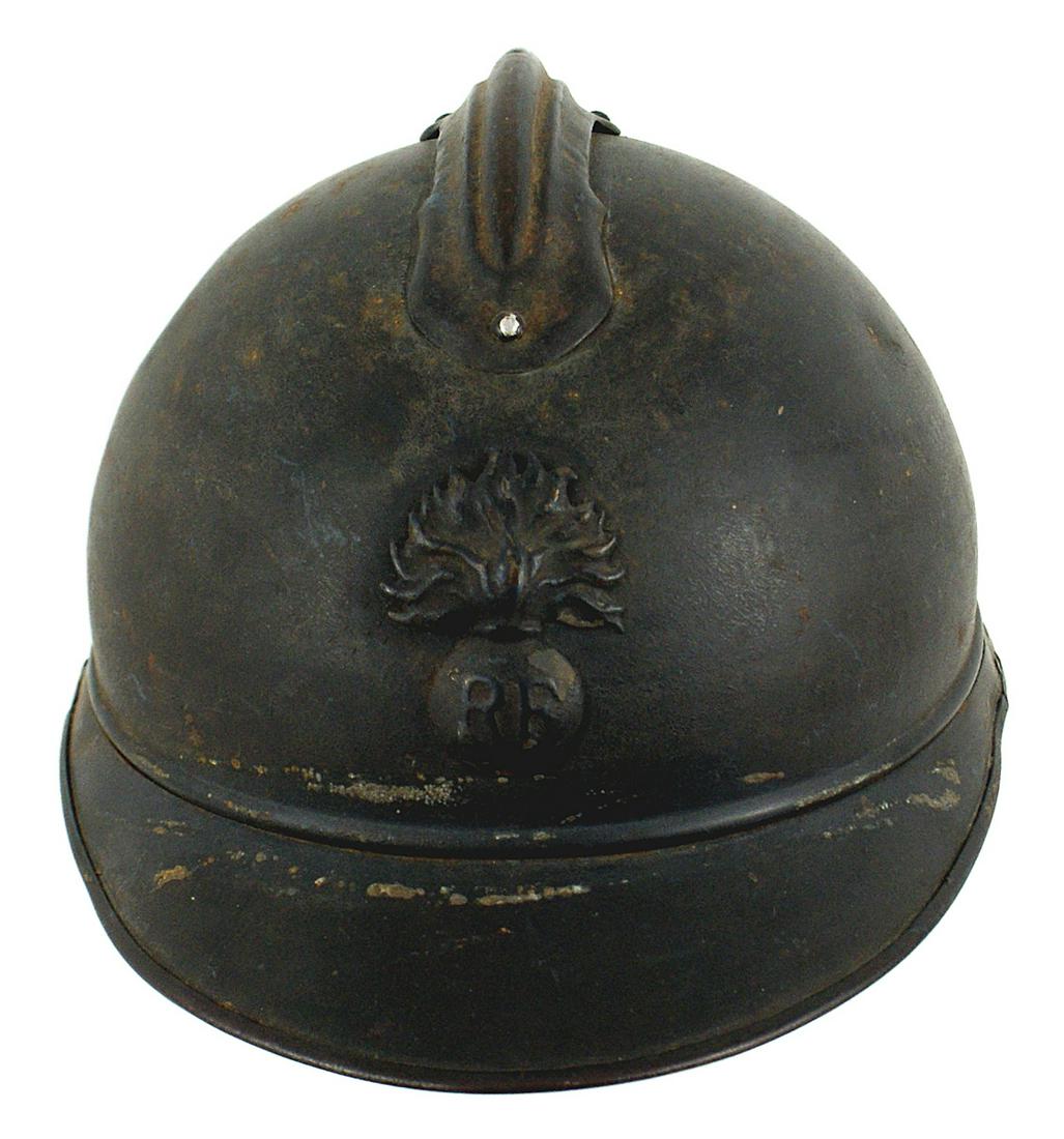 WWI French M1915 Adrian steel helmet: E-027 WWI French M1915 Adrian steel helmet. Flaming bomb with "RF" badge and short comb. Darkened finish. Seven tongue leather liner shows some wear. No chinstrap. About II
