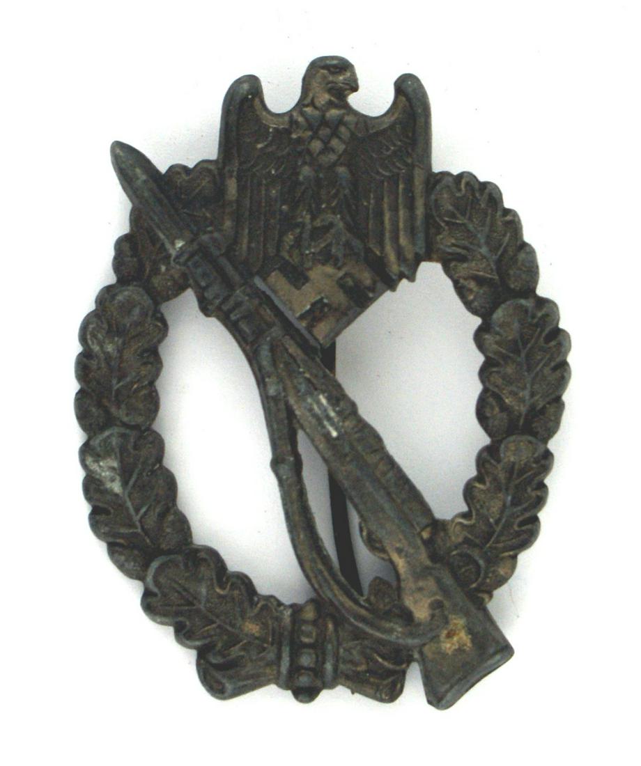 German WWII Infantry Assault Badge: B-074 German WWII Infantry Assault Badge - Silver (appears Bronze but has minute specks of Silver). Convex shape. Rifle with fixed bayonet on an open oak leaf wreath with an eagle/swastika at the top.
